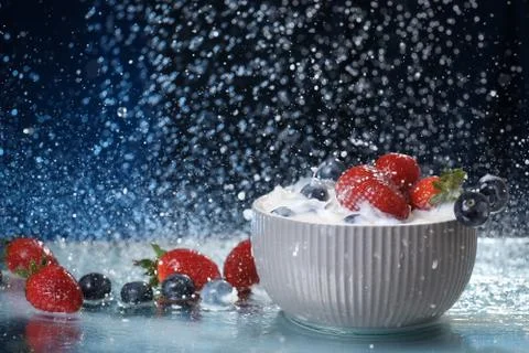 Milk splash close up of falling berries in a grey plate of milk. Stock Photos