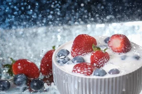 Milk splash close up of falling berries in a grey plate of milk. Foto stock