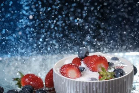 Milk splash close up of falling berries in a grey plate of milk. Stock Photos