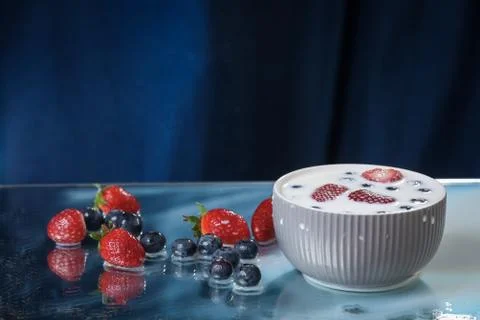 Milk splash close up of falling berries in a grey plate of milk. Stock Photos