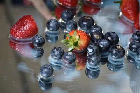 Milk splash close up of falling berries in a grey plate of milk. Stock Photos
