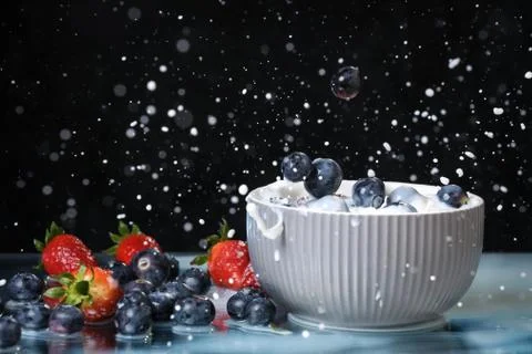 Milk splash close up of falling berries in a grey plate of milk. Stock Photos