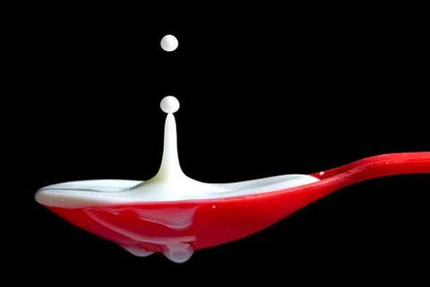 Milk splash in a red spoon Foto stock