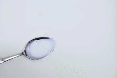 Milk Splash On Silver Spoon Stock Photos