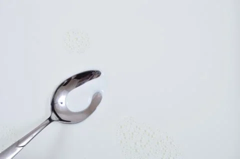 Milk Splash On Silver Spoon Stock Photos