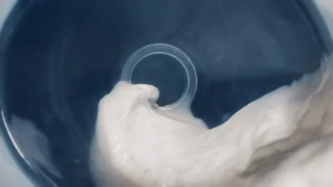 Milk stream flows through the bottle and runs outside in slow motion, macro Stock Footage 128351553