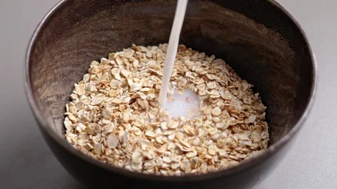 Milk stream pouring into bowl with oat flakes. Stock Footage 331343281