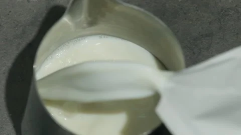 Milk stream splashes poured into stainless steel pitcher Stock Footage 306593390