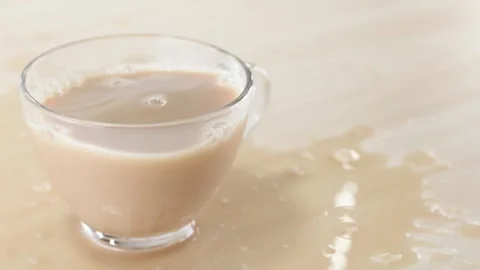 Milk Tea Splashing and Spilling from Glass Cup on Wooden Table Stock Footage 346013195