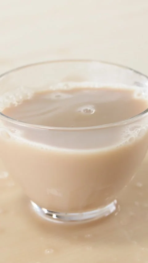 Milk Tea Splashing and Spilling from Glass Cup on Table Stock Footage 346271638
