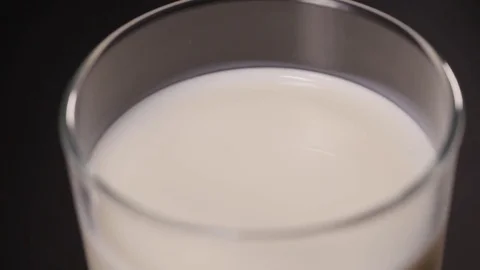Milk in a transparent glass, the camera is located above a glass Stock Footage 75224014