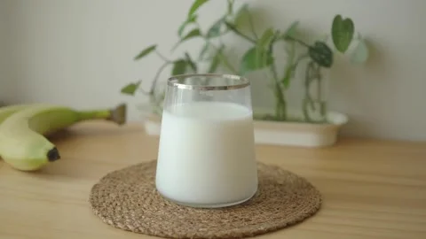 Milk on a wooden table with plants in the background Stock Footage 340374543