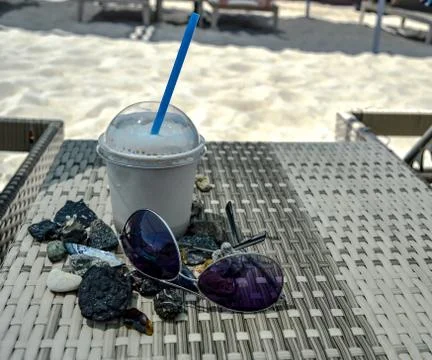 Milkshake in a plastic cup on a table with glasses and pebbles Foto stock