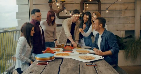 Millenial friends group drinking beer and sharing pizza slices on the rooftop at Stock Footage 117184053