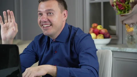 Millenial man greets household off-screen and gestures that he needs to continue Stock Footage 169747484