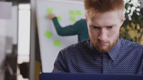 Millennial American man using laptop computer sitting at table in office meeting Stock Footage 115650533