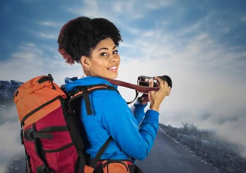Millennial backpacker with camera against misty road Stock Photos