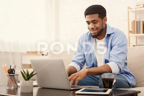 Millennial black man working on laptop in home office Stock Photos