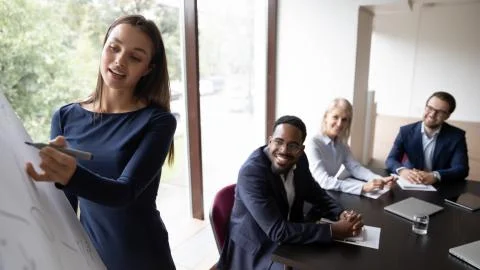 Millennial coach using flipchart give presentation to multiethnic businesspeople Stock Photos