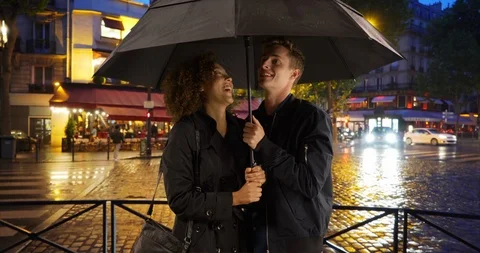 Millennial couple stand under umbrella on rainy evening in Paris Stock Footage 85592257
