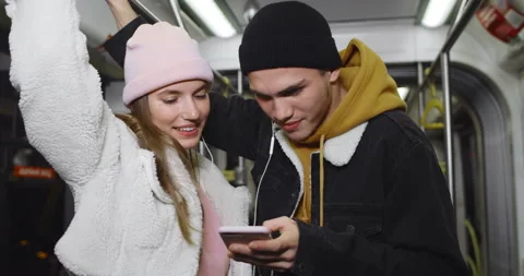 Millennial couple talking and looking at mobilephone screen. Pretty girl and her Stock Footage 136825336