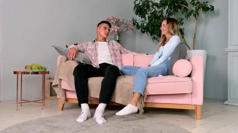 Millennial couple talking laughing sitting on couch, smiling male and female Stock Footage 161838271
