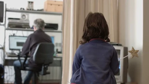 Millennial daughter watching tv while dad is working on pc 動画素材 73732782