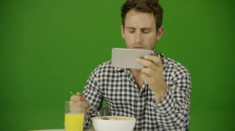 A millennial drops his smartphone into his breakfast while watching videos Stock Footage 64751767