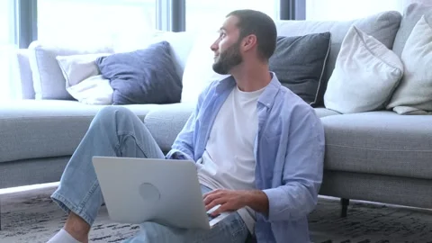 Millennial freelancer sitting on the floor in a bright living room, focused Stock Footage 344780707
