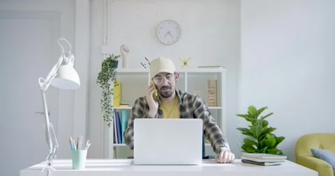 Millennial freelancer talking in a phone call on a home computer desk Stock Footage 287466160