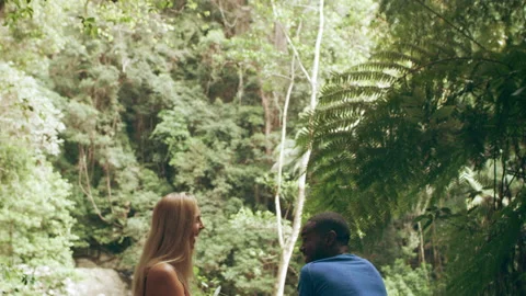 Millennial friends laughing in front of small waterfall in an Australian rainfor Video stock 199460021