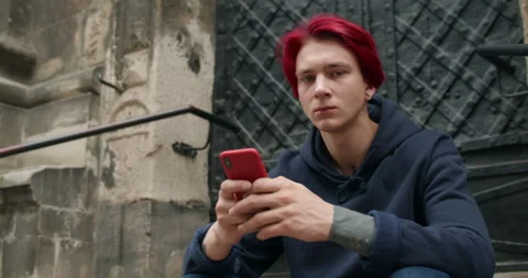 Millennial guy with earring and tattoos looking at phone screen and than to Stock-Footage 144270435