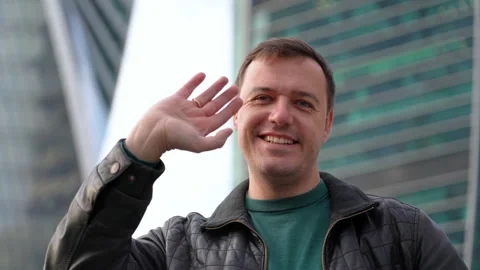 Millennial guy looking at camera, smiling and waving hello greeting gesture Stock Footage 168934536