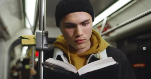 Millennial guy reading interesting book while going in public transport. Young Stock Footage 136290285