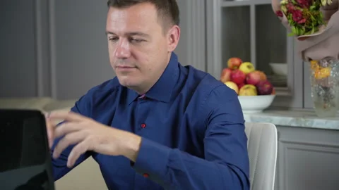 Millennial guy relaxing at kitchen with notebook on table, he is sitting with Stock Footage 169228409