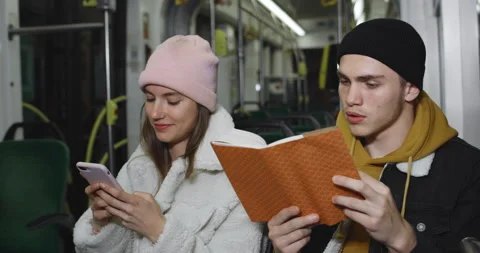 Millennial guy using reading book while sitting near his lovely girlfriend Stock Footage 136827426