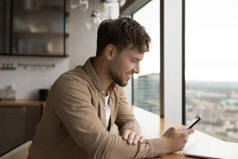 Millennial guy using smartphone smile enjoy personal chat Stock Photos
