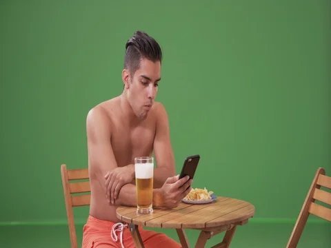 Millennial Hispanic man drinking beer and eating on green screen Stock Footage