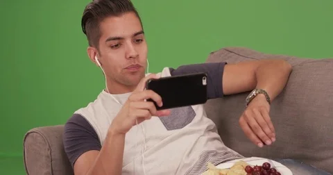 Millennial Hispanic man laughing and texting on green screen Video stock 79371518