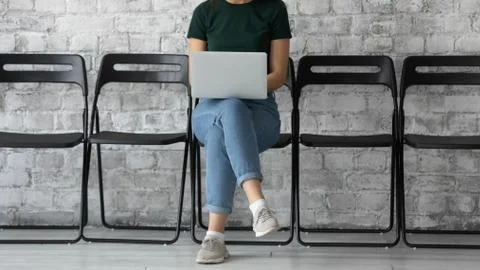 Millennial lady applicant using laptop and waiting for recruiter appointment Foto stock