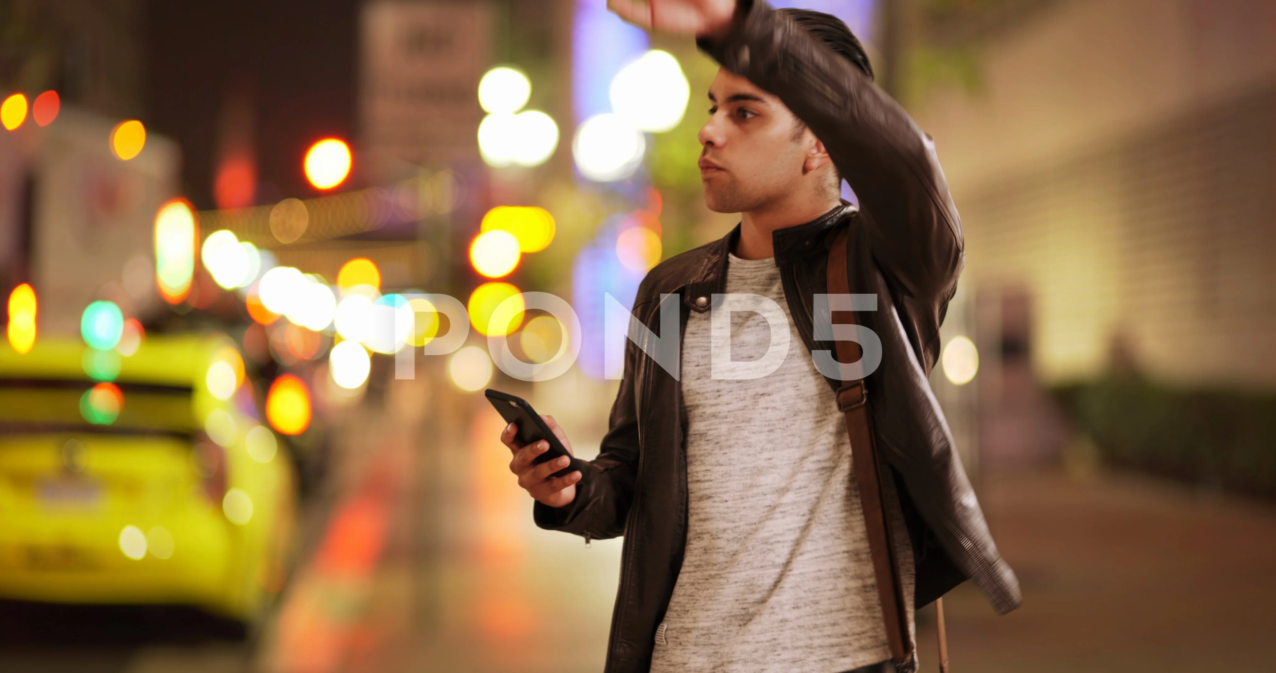 Millennial Latino man calling for taxi or ride sharing service on city  street