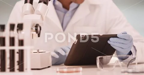 Millennial Latino medical scientist in laboratory using tablet computer Stock Photos