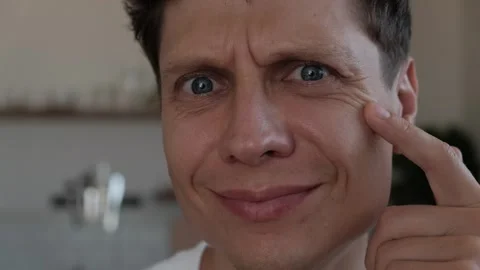 Millennial man confronting his changing appearance and signs of aging in mirror Stockbeeldmateriaal 346709786