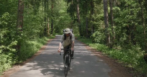 Millennial man cycling alone on forest road, front view Stock Footage 311920472