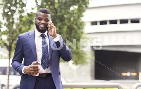 Millennial man in formal suit drinking coffee and using cellphone Stock Photos