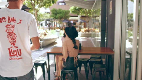 Millennial man joins two friends with coffee outside a coffee shop in Australia Stock Footage 199458425