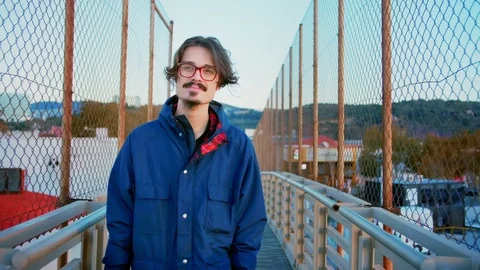 Millennial man looking to the camera and walking by small bridge in cold morning Stock Footage 100863323