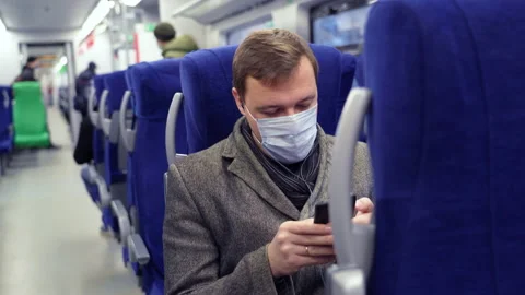 Millennial man in mask commuting on train sitting listening to music on mobile Stock Footage 168106042