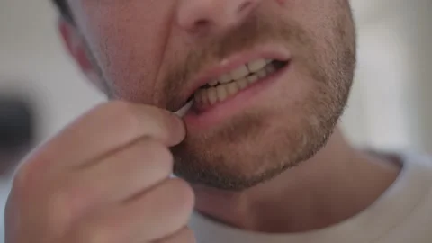 Millennial man meticulously cleaning between his teeth with a toothpick during Vidéo 335201178