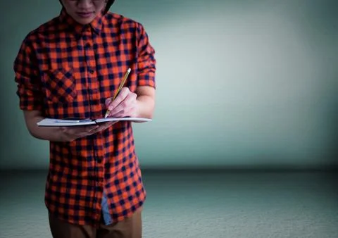 Millennial man mid section writing in notepad against green room Stock Photos